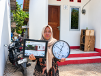 Perempuan Menunjukkan Plakat dan Jam Rumah Layak Huni